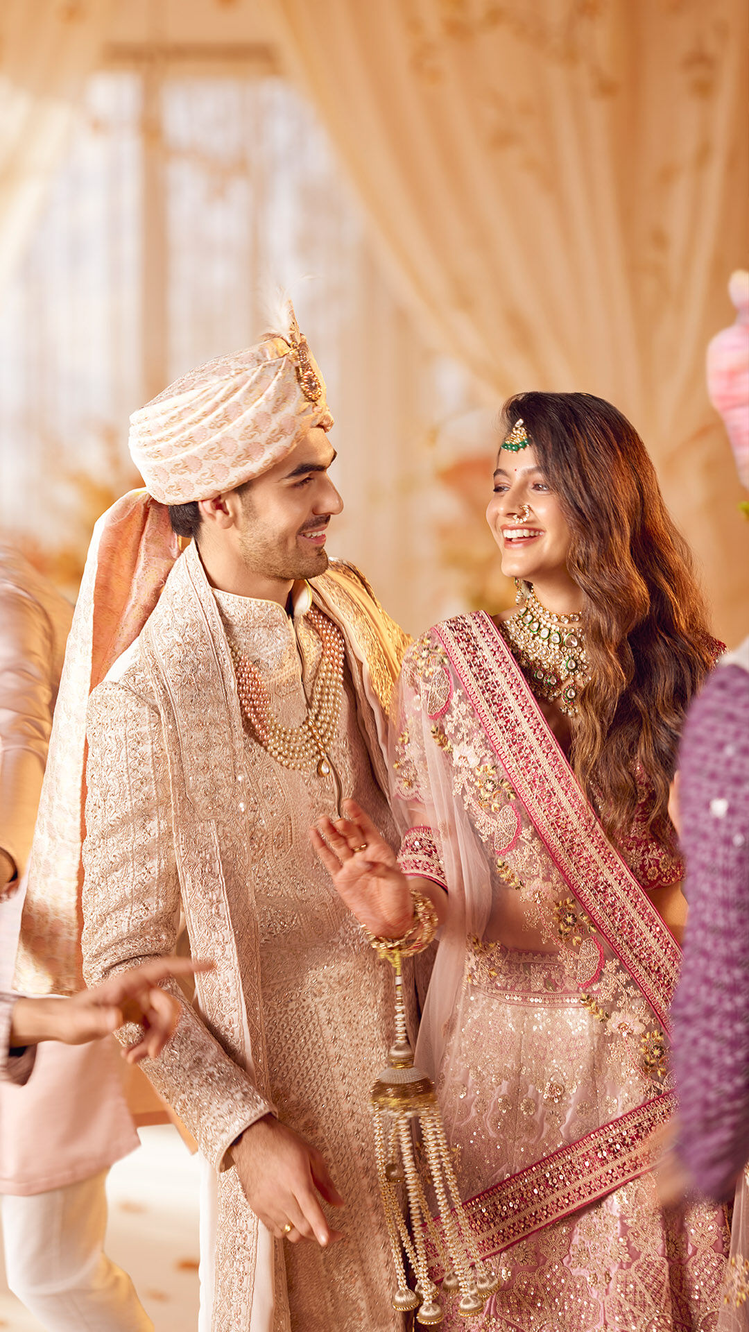 Bride wearing pink lehenga and groom wearing cream and gold sherwani